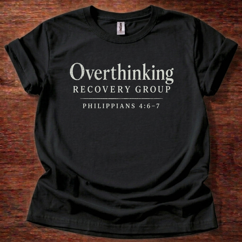 Black t-shirt with 'Overthinking Recovery Group Philippians 4:6-7' text on a wooden surface