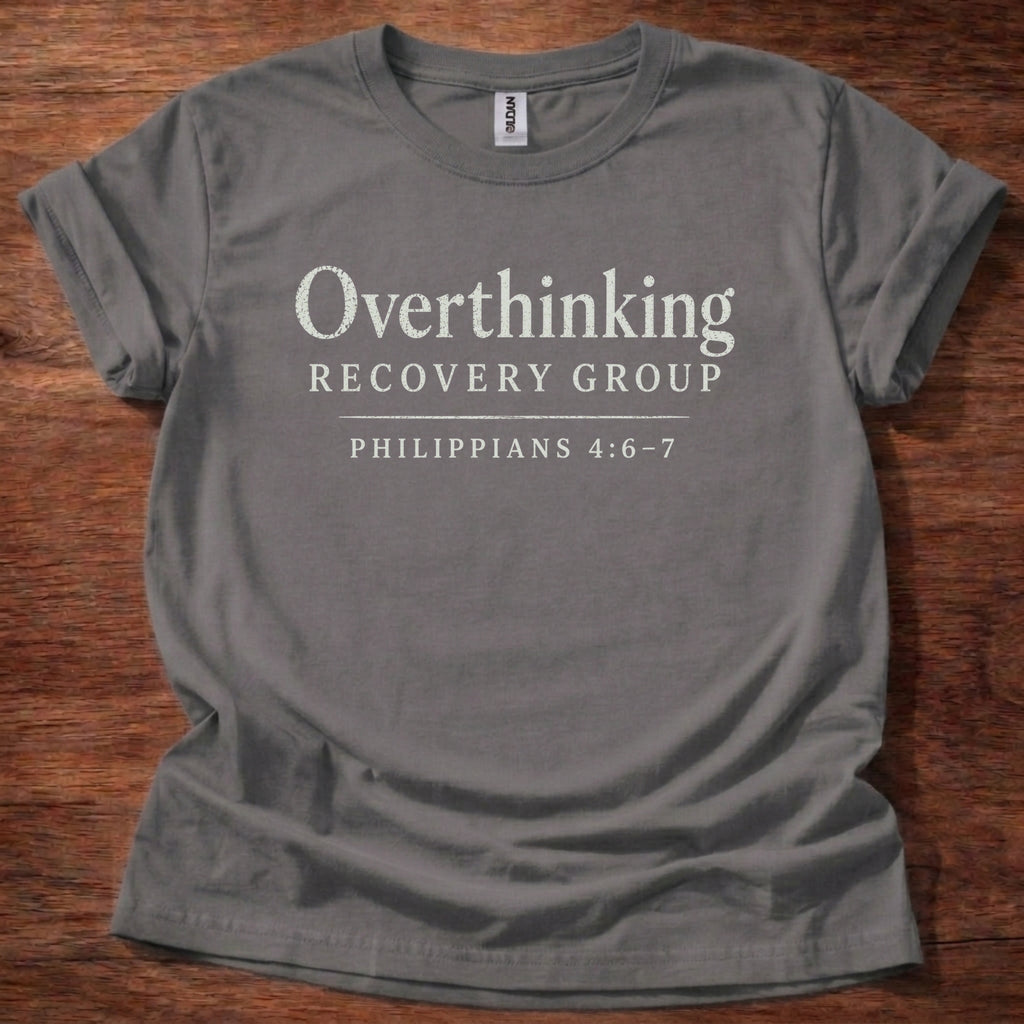 Gray t-shirt with 'Overthinking Recovery Group Philippians 4:6-7' text on a wooden surface