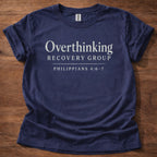 Navy blue t-shirt with 'Overthinking Recovery Group' text on a wooden surface