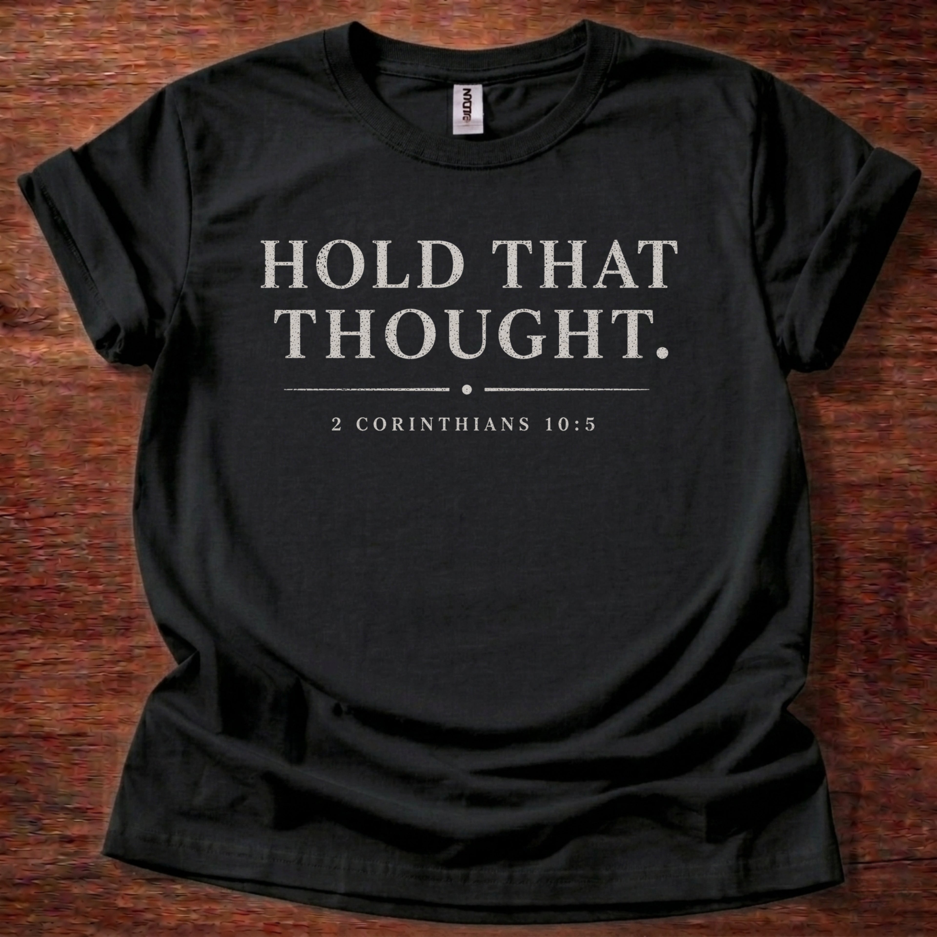 Black t-shirt with 'Hold That Thought' text on a wooden surface