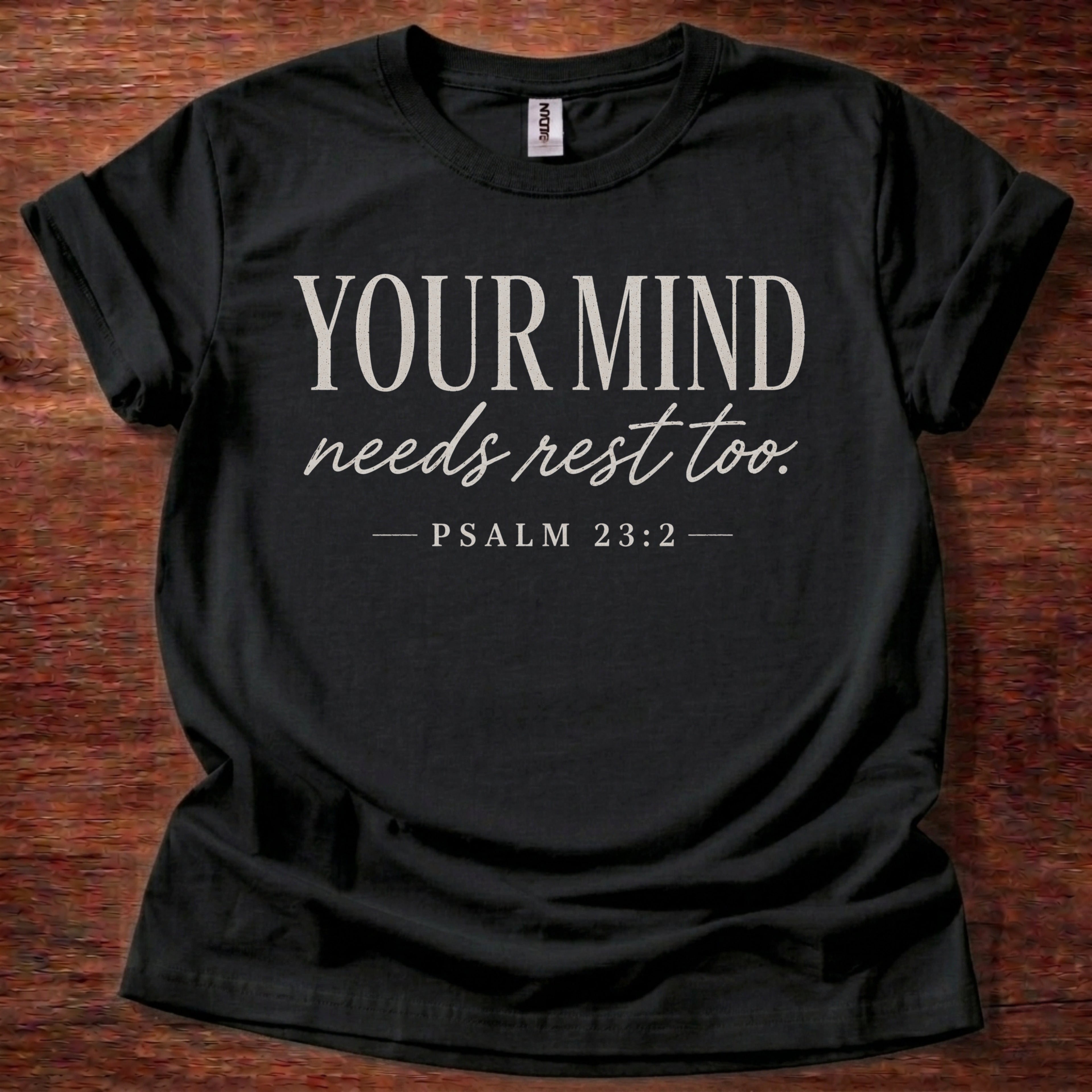 Black t-shirt with 'Your Mind Needs Rest Too' text on a wooden surface