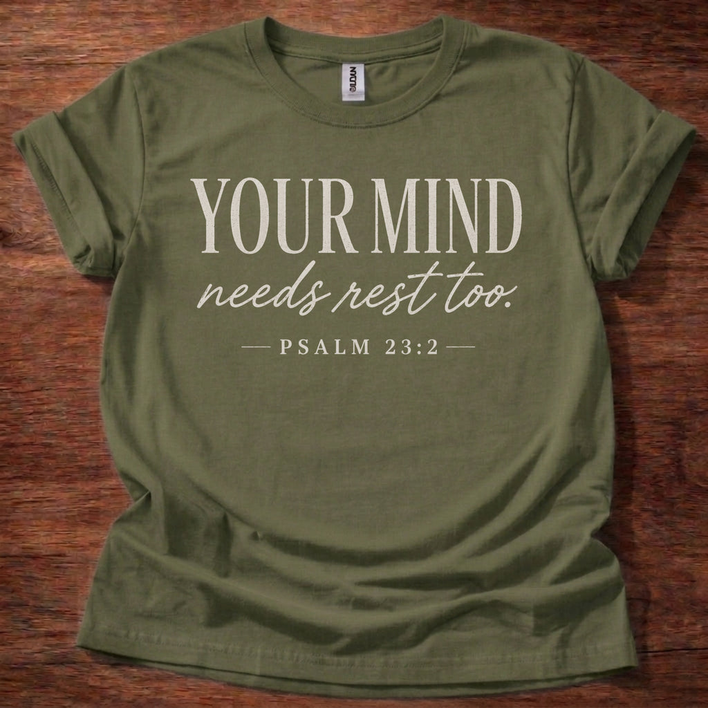 Green t-shirt with 'Your Mind Needs Rest Too' text on a wooden surface