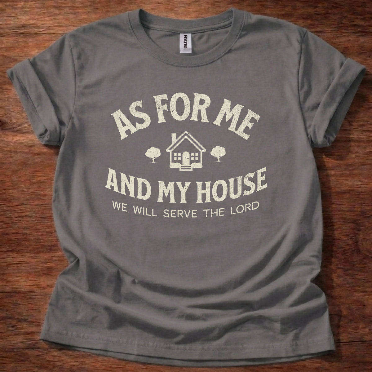 Cream farmhouse-style t-shirt with a cottage and tree icon and the text 'As For Me And My House, We Will Serve The Lord' — Joshua 24:15