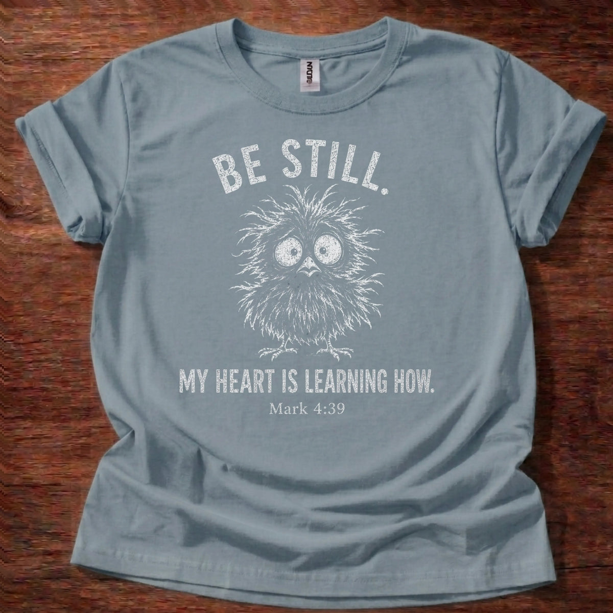 White fine-line owl illustration t-shirt with the text 'Be Still. My Heart Is Learning How.' and Mark 4:39