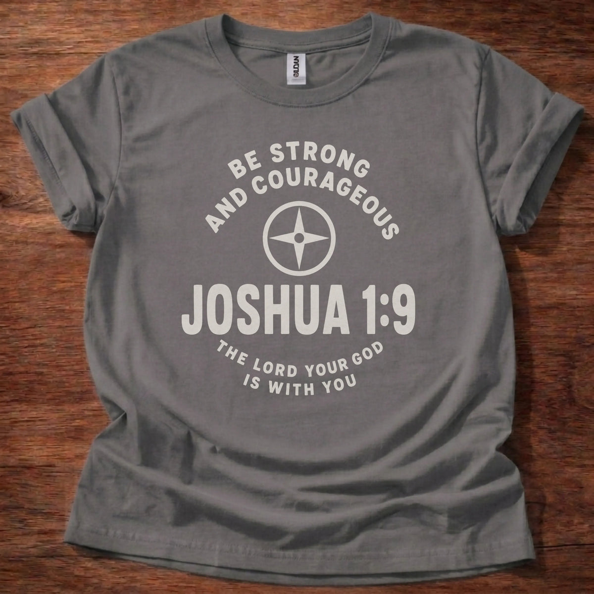 Cream compass icon t-shirt with the text 'Be Strong And Courageous' arched above and 'Joshua 1:9' below