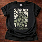 Black t-shirt featuring a floral design with the phrase “A Praying Woman” printed on the front
