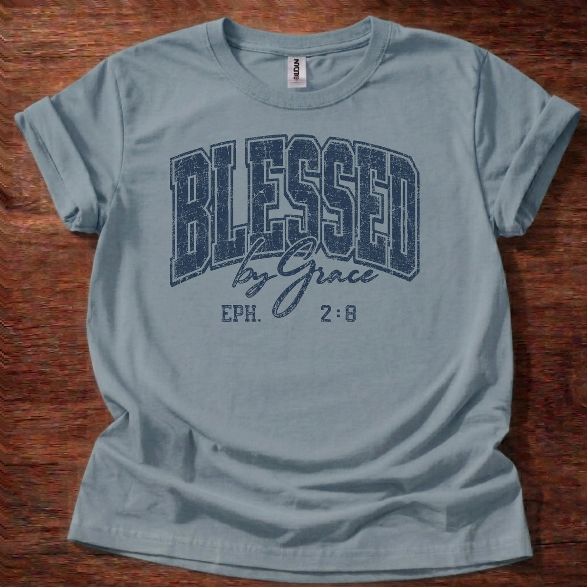 Navy distressed varsity-style t-shirt reading 'Blessed by Grace' with cursive script and Ephesians 2:8 citation