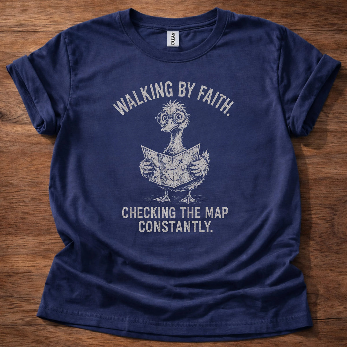 White fine-line illustration of a duck reading a map wearing glasses with the text 'Walking By Faith. Checking The Map Constantly.'