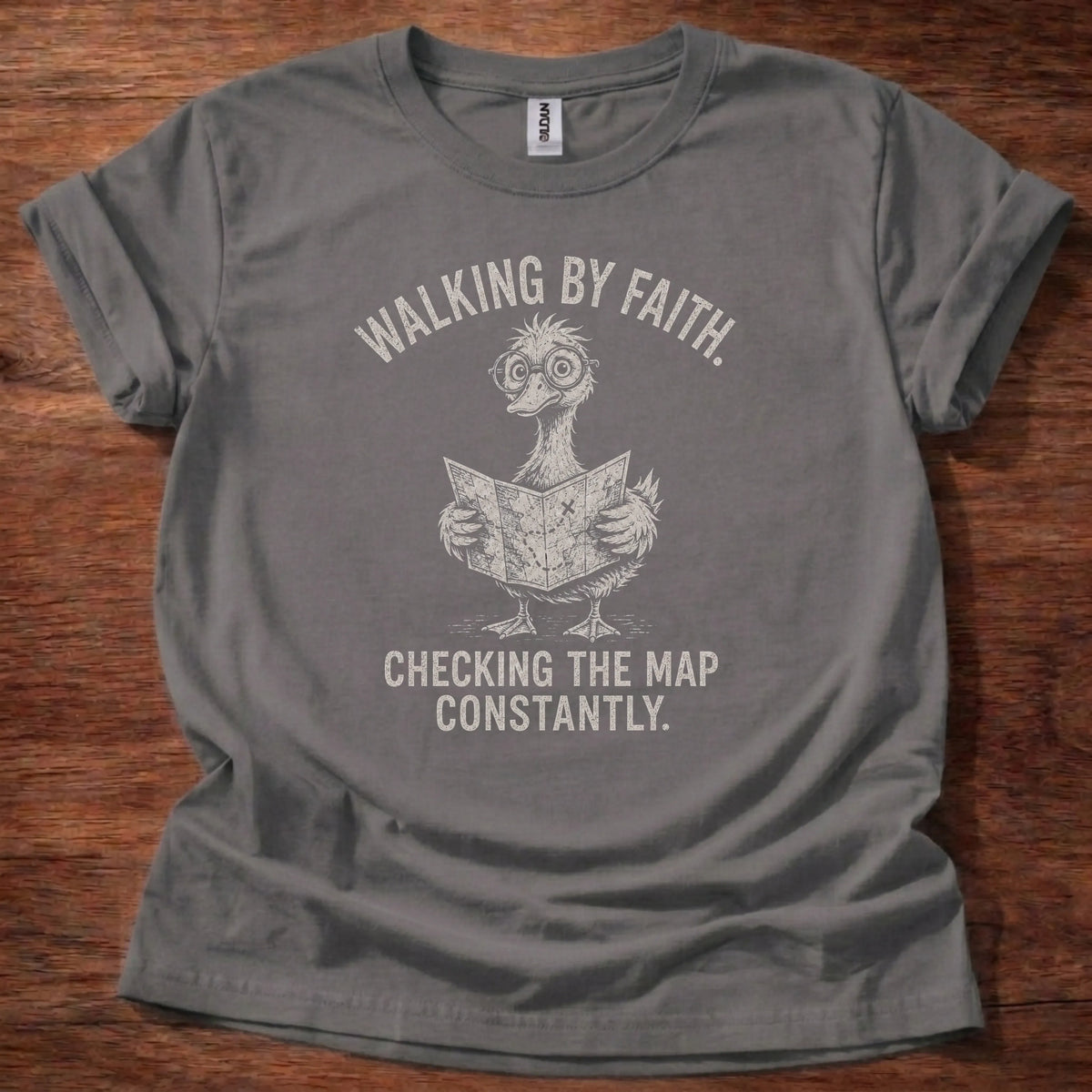 White fine-line illustration of a duck reading a map wearing glasses with the text 'Walking By Faith. Checking The Map Constantly.'