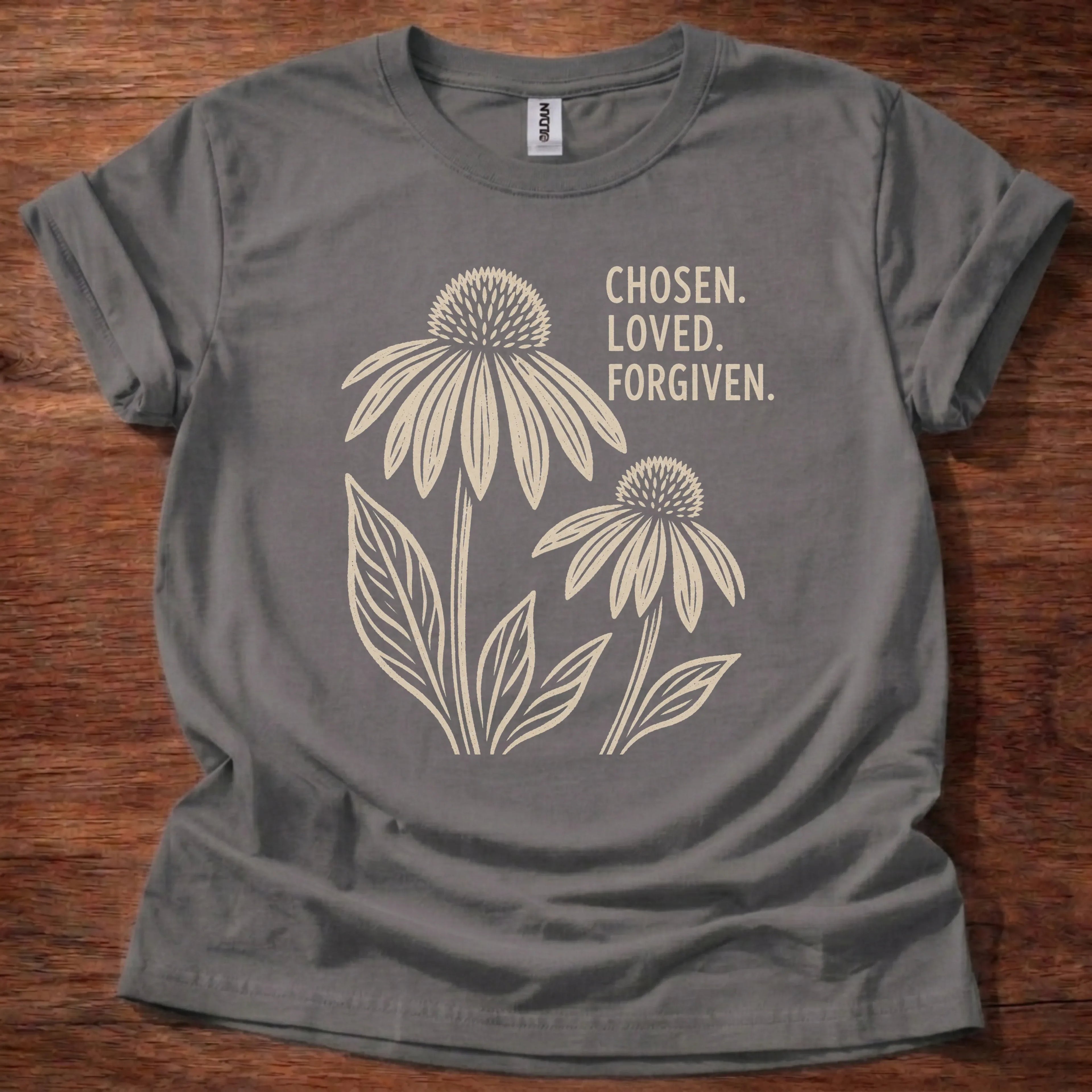 Cream linocut-style coneflower illustration t-shirt with the stacked text 'Chosen. Loved. Forgiven.'