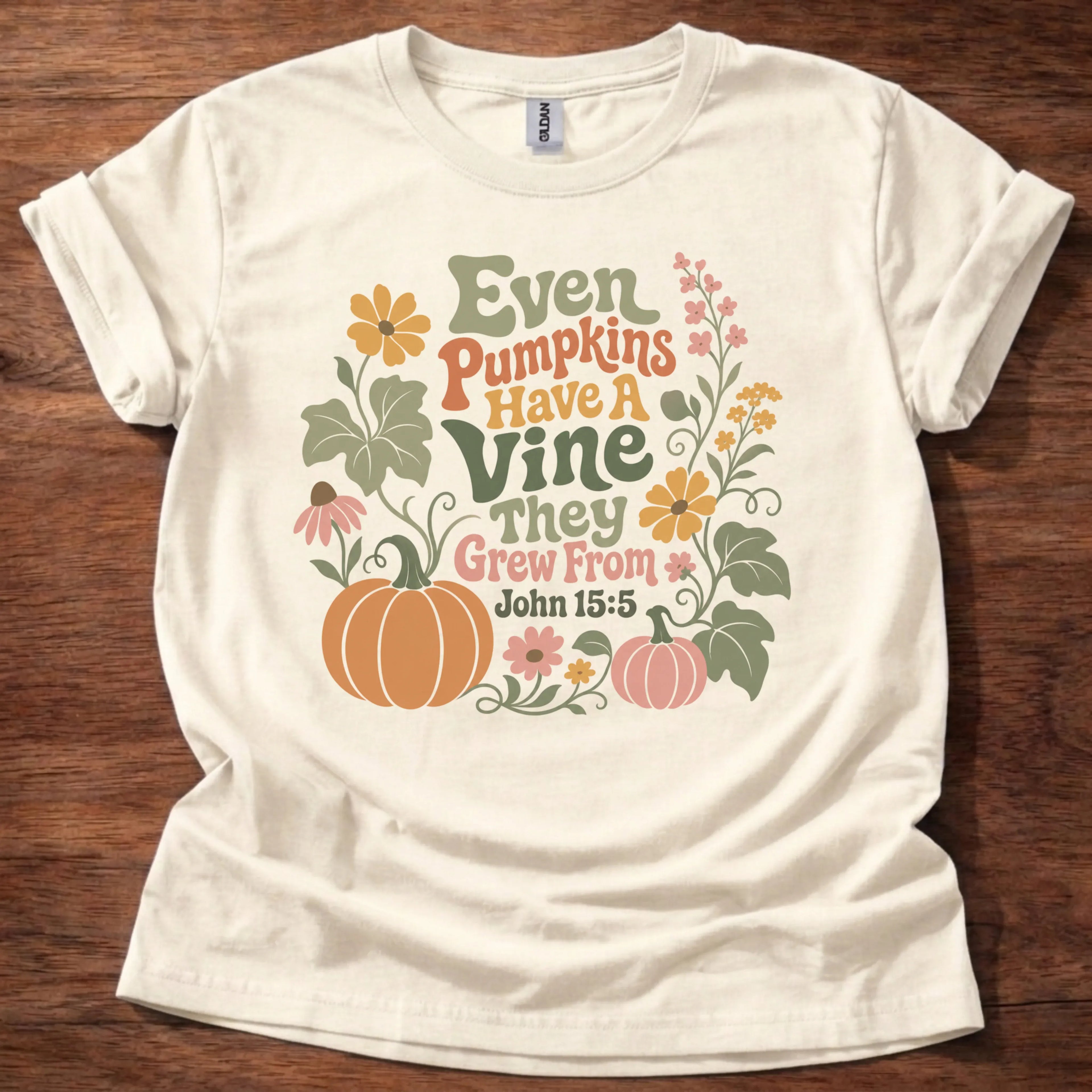Colorful retro wildflower and pumpkin illustration t-shirt with the text 'Even Pumpkins Have A Vine They Grew From' — John 15:5