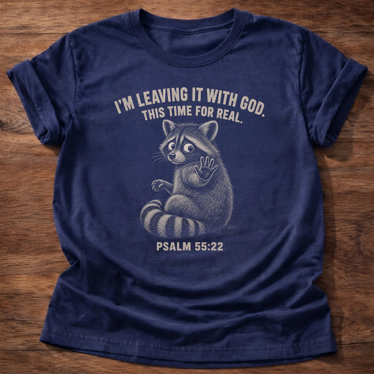 Navy t-shirt printed with 'I'm leaving it with God, this time for real' raccoon graphic, Psalm 55:22 faith based tee