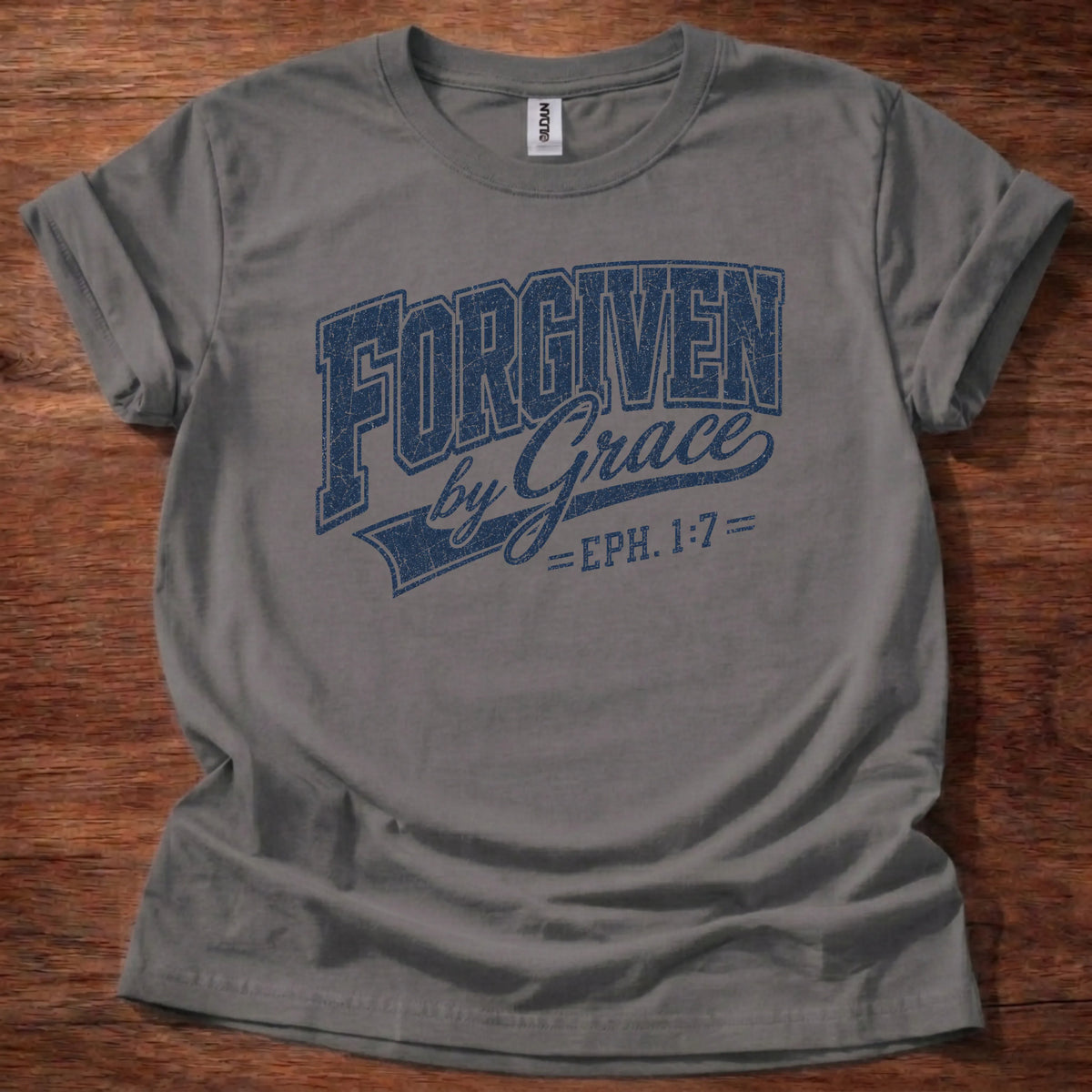 Navy distressed varsity-style t-shirt reading 'Forgiven by Grace' with cursive script and Ephesians 1:7 citation