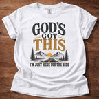God’s Got This I’m Just Here for the Ride Christian shirt with mountain and sunrise graphic on beige t-shirt, inspirational faith design