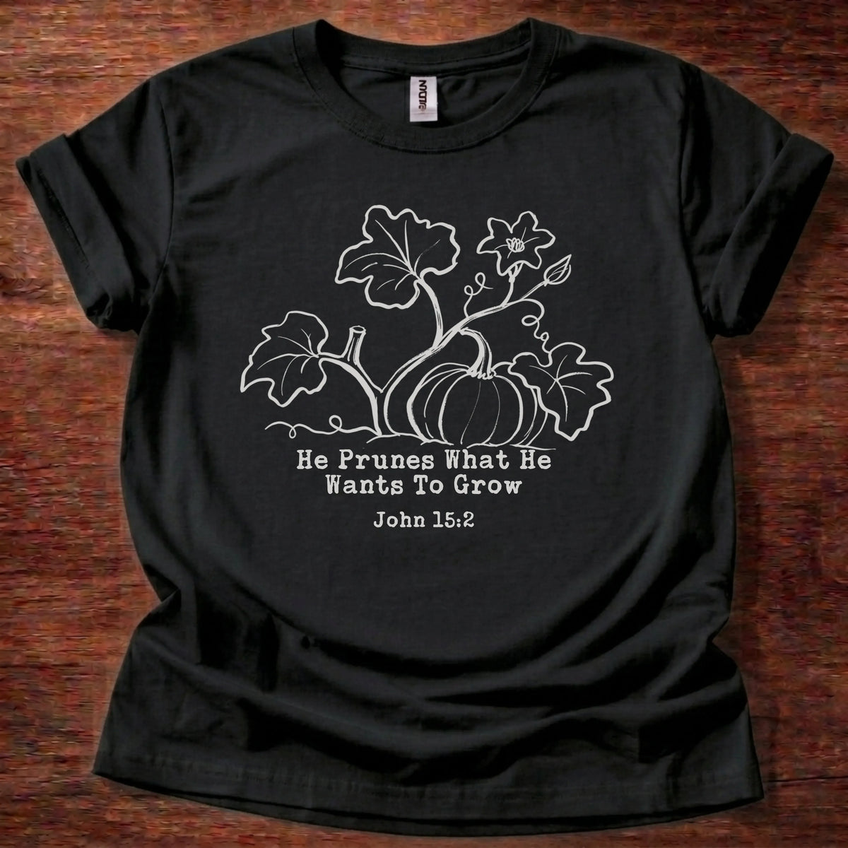 Cream tonal pumpkin vine illustration t-shirt with the text 'He Prunes What He Wants To Grow' and John 15:2