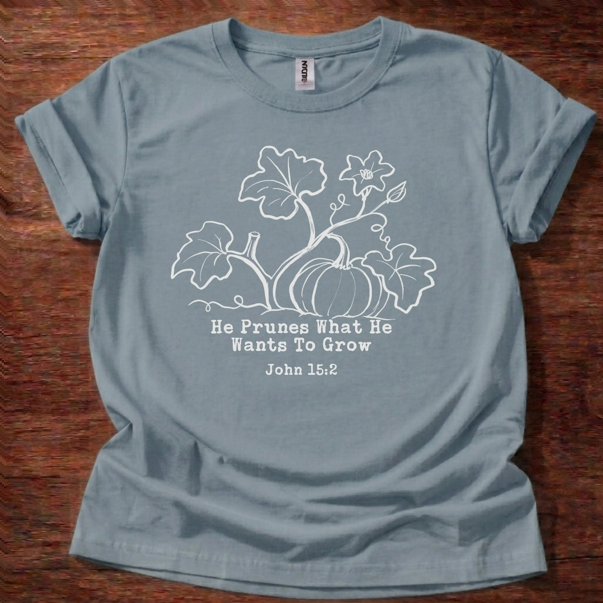 Cream tonal pumpkin vine illustration t-shirt with the text 'He Prunes What He Wants To Grow' and John 15:2