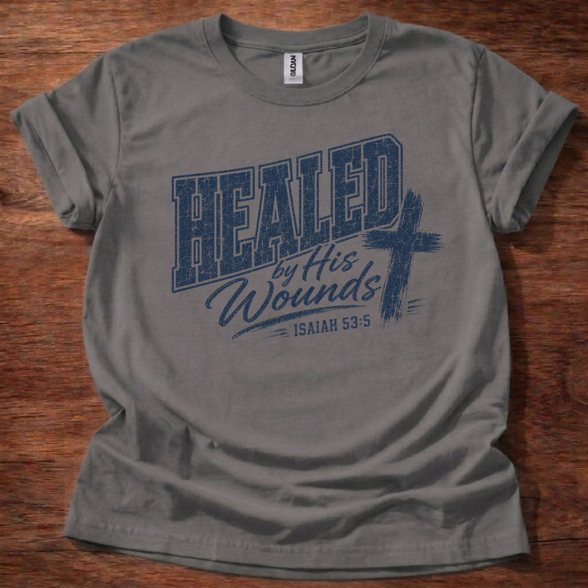 Navy distressed varsity-style t-shirt reading 'Healed by His Wounds' with a distressed cross graphic and Isaiah 53:5 citation