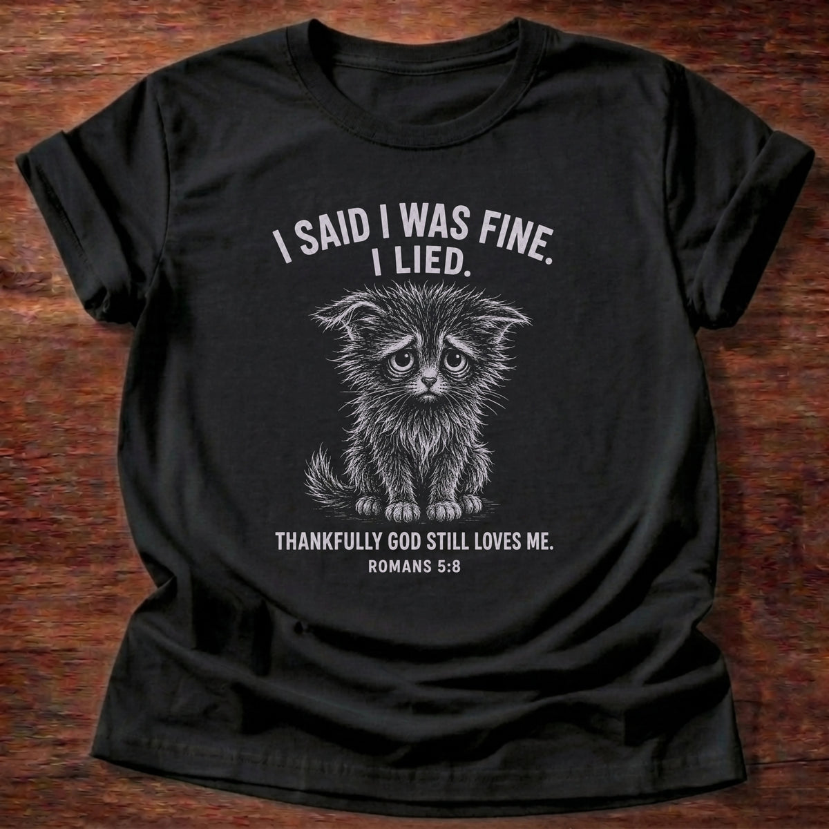 Black t-shirt printed with 'I said I was fine. I lied. Thankfully God still loves me.' cat graphic, a Romans 5:8 faith based gift