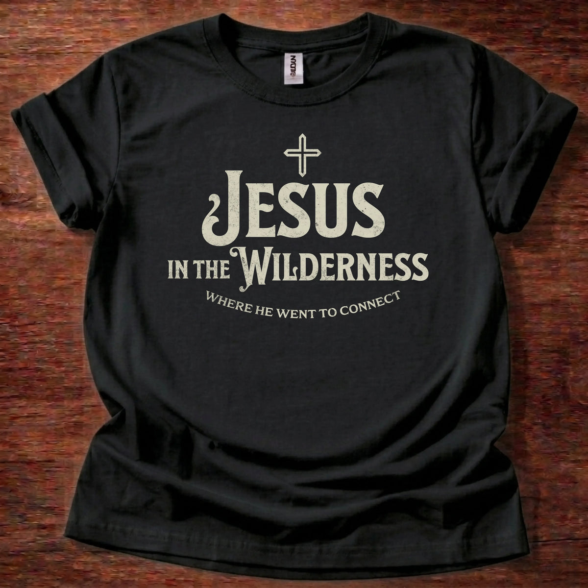Cream vintage-lettering t-shirt with a small cross icon and the text 'Jesus In The Wilderness, Where He Went To Connect'