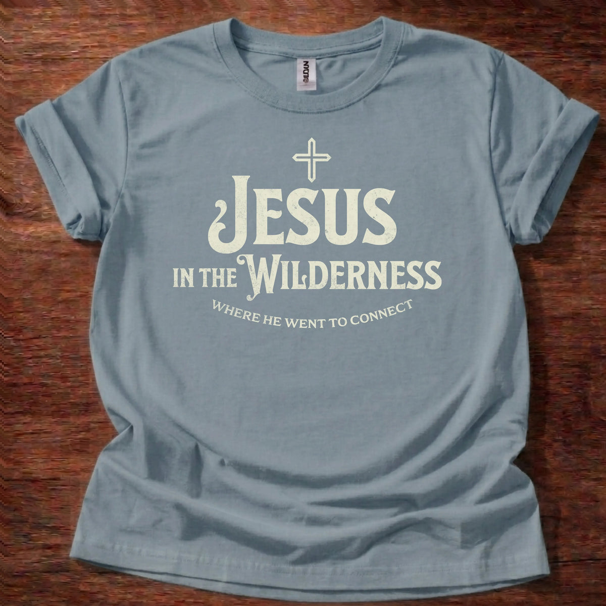 Cream vintage-lettering t-shirt with a small cross icon and the text 'Jesus In The Wilderness, Where He Went To Connect'