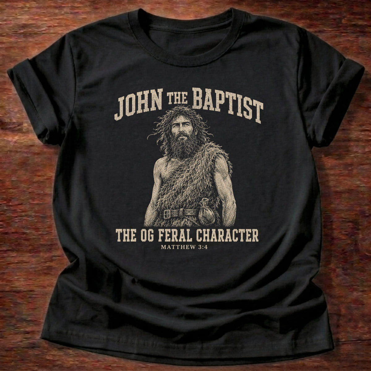Black t-shirt reading 'John the Baptist, the OG feral character' with Matthew 3:4 reference, a funny Christian Bible humor shirt