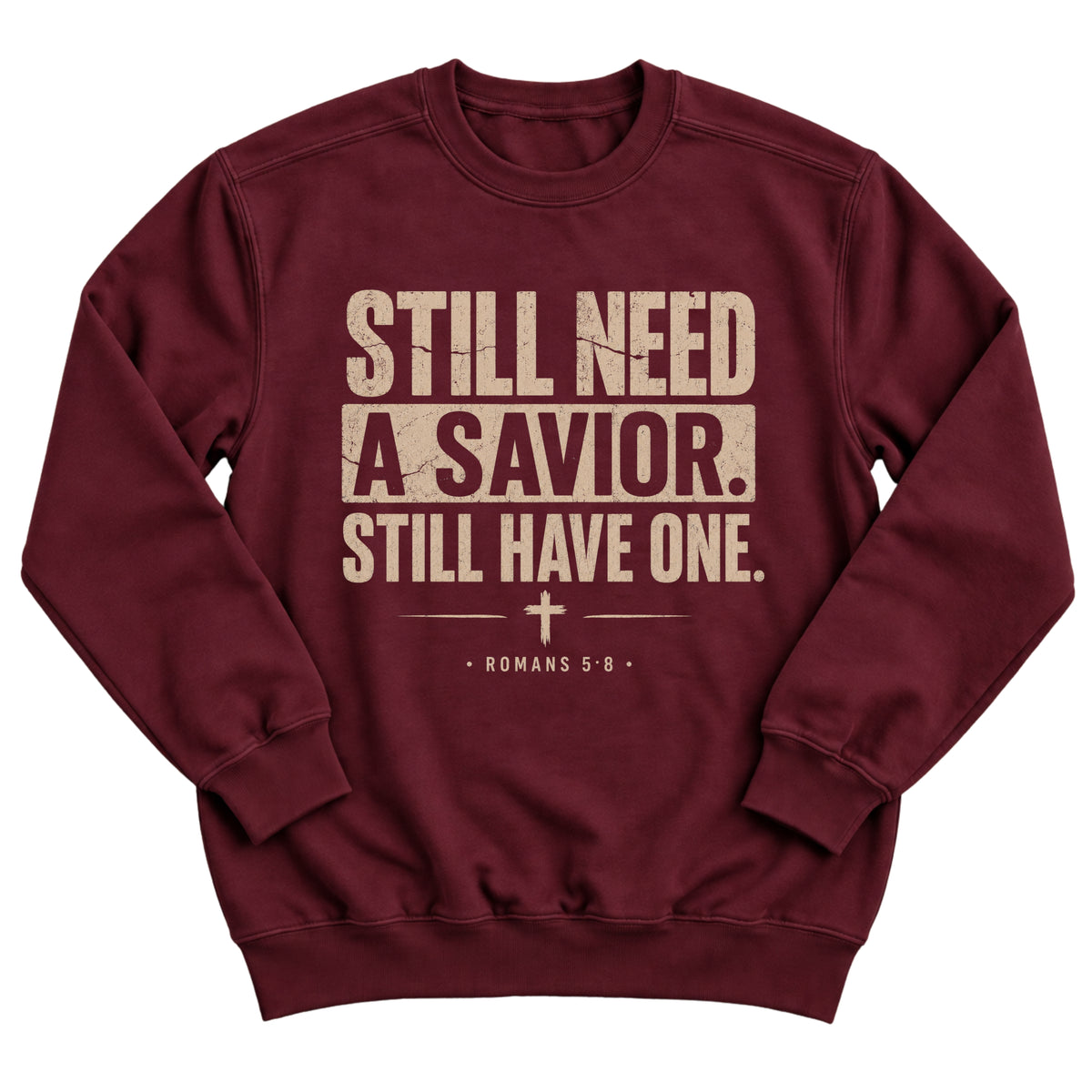 Maroon crewneck sweatshirt with bold distressed lettering reading Still Need A Savior. Still Have One. with a small cross and Romans 5:8