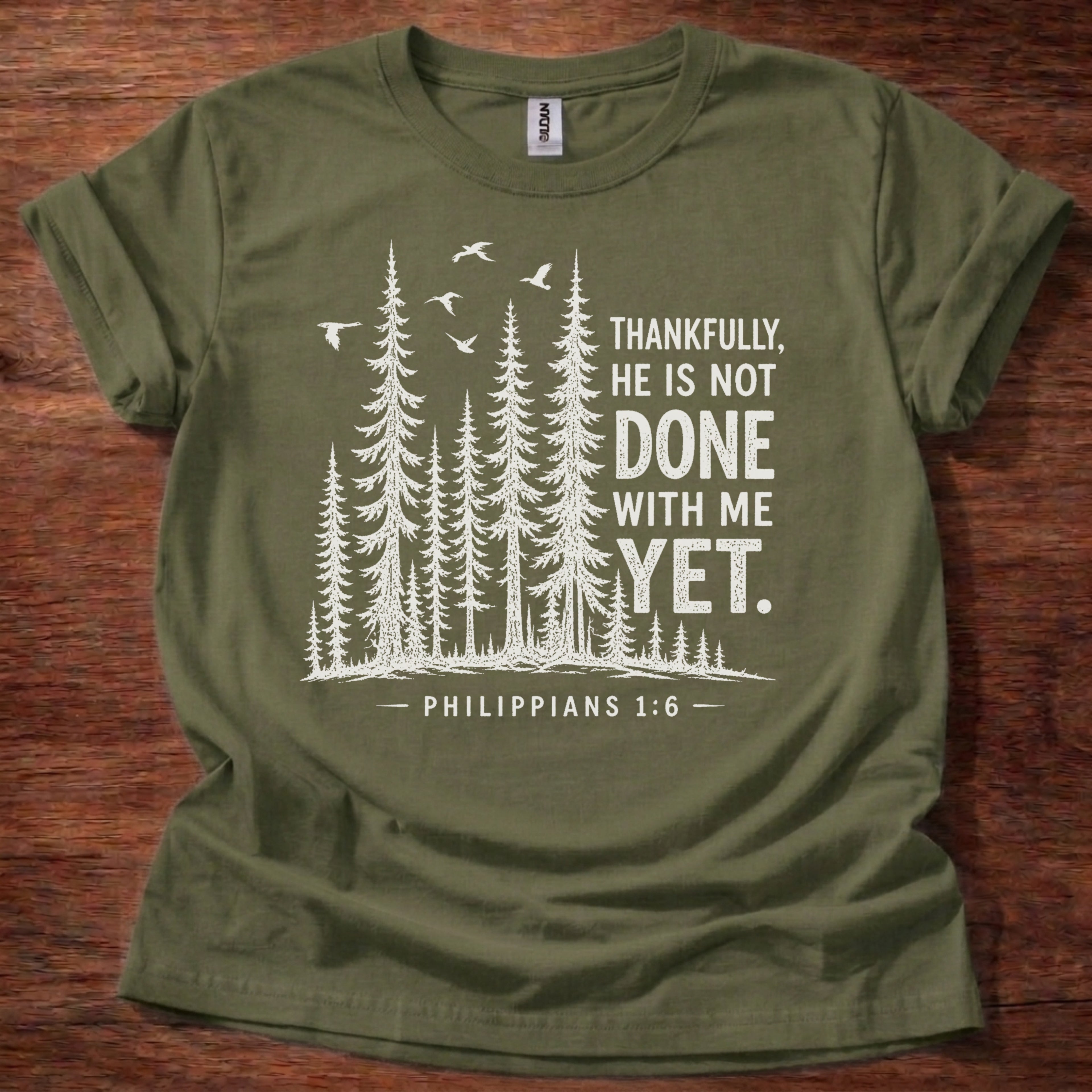 Military Green Christian t-shirt with forest graphic and “Thankfully, He is not done with me yet” Philippians 1:6 design