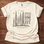Natural Christian t-shirt with forest graphic and “Thankfully, He is not done with me yet” Philippians 1:6 design