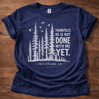 Navy Christian t-shirt with forest graphic and “Thankfully, He is not done with me yet” Philippians 1:6 design