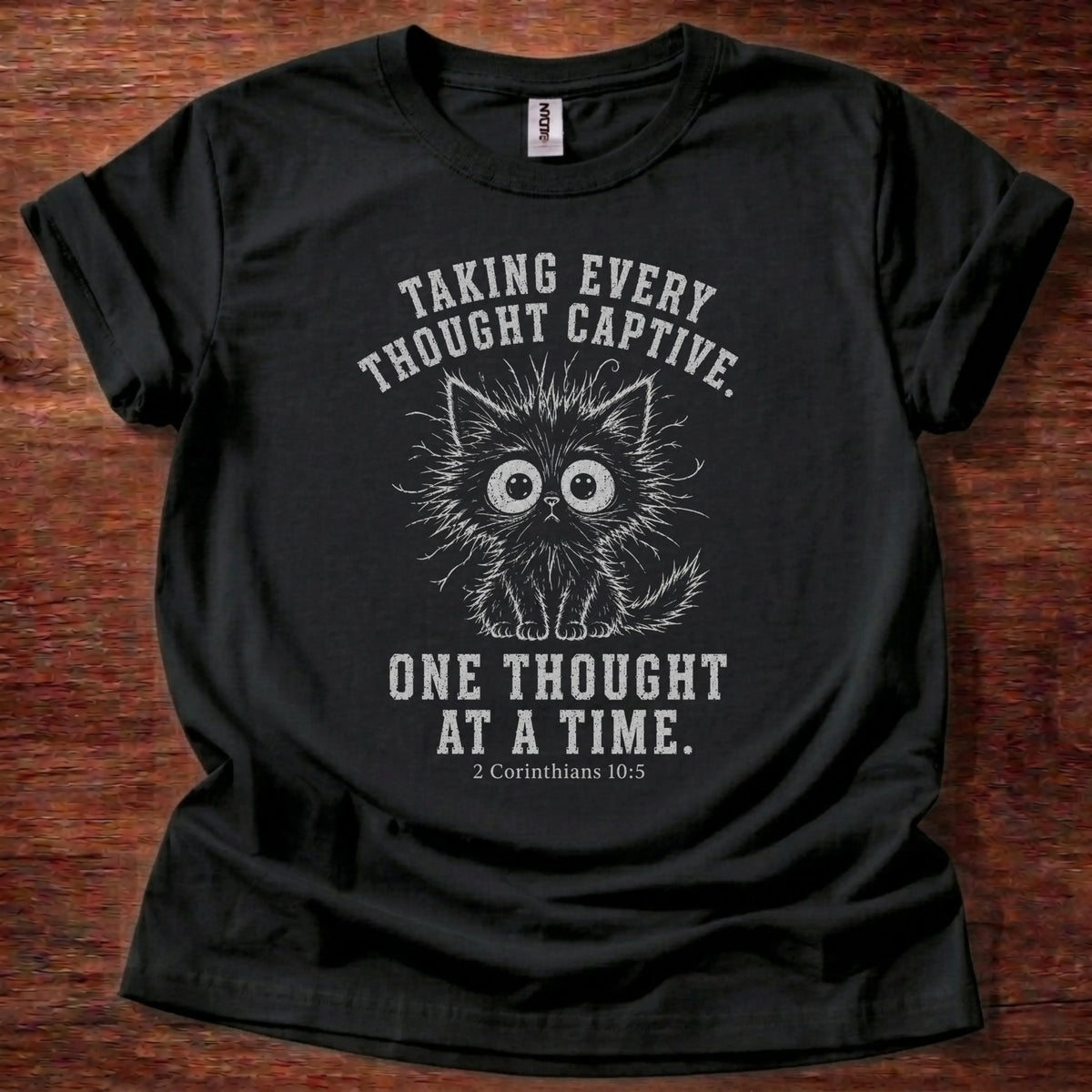 White fine-line kitten illustration t-shirt with the text 'Taking Every Thought Captive. One Thought At A Time.' and 2 Corinthians 10:5