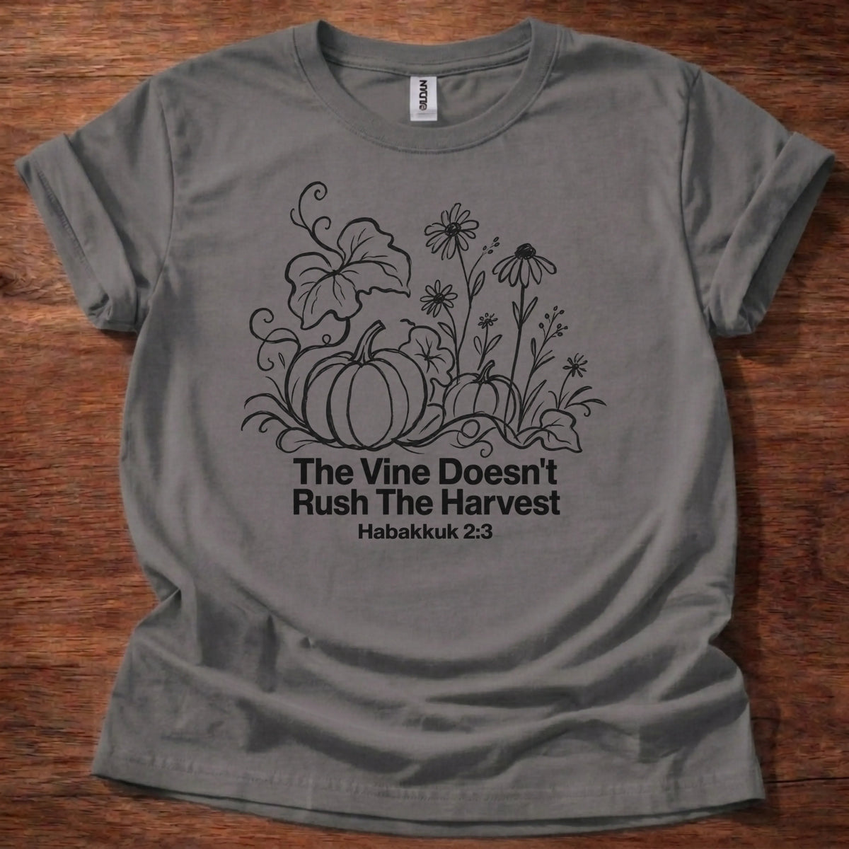 Hand-sketched black and white pumpkin and wildflower illustration t-shirt with the text 'The Vine Doesn't Rush The Harvest' — Habakkuk 2:3