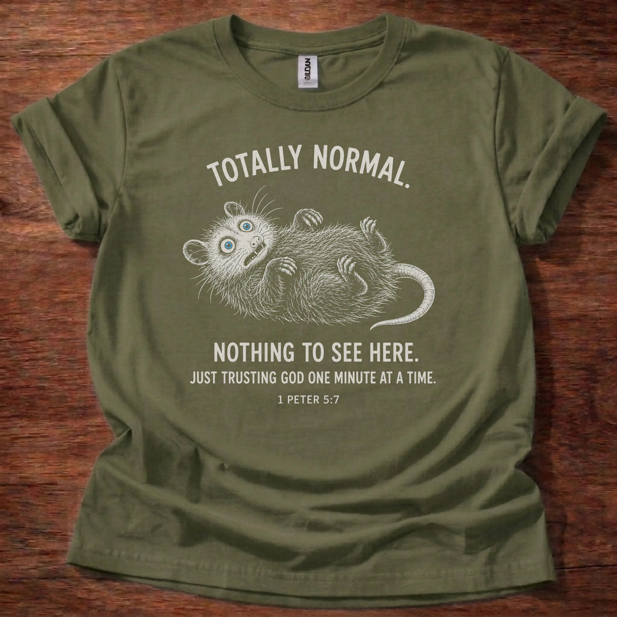 White fine-line opossum illustration playing dead t-shirt with the text 'Totally Normal. Nothing To See Here. Just Trusting God One Minute At A Time.' and 1 Peter 5:7