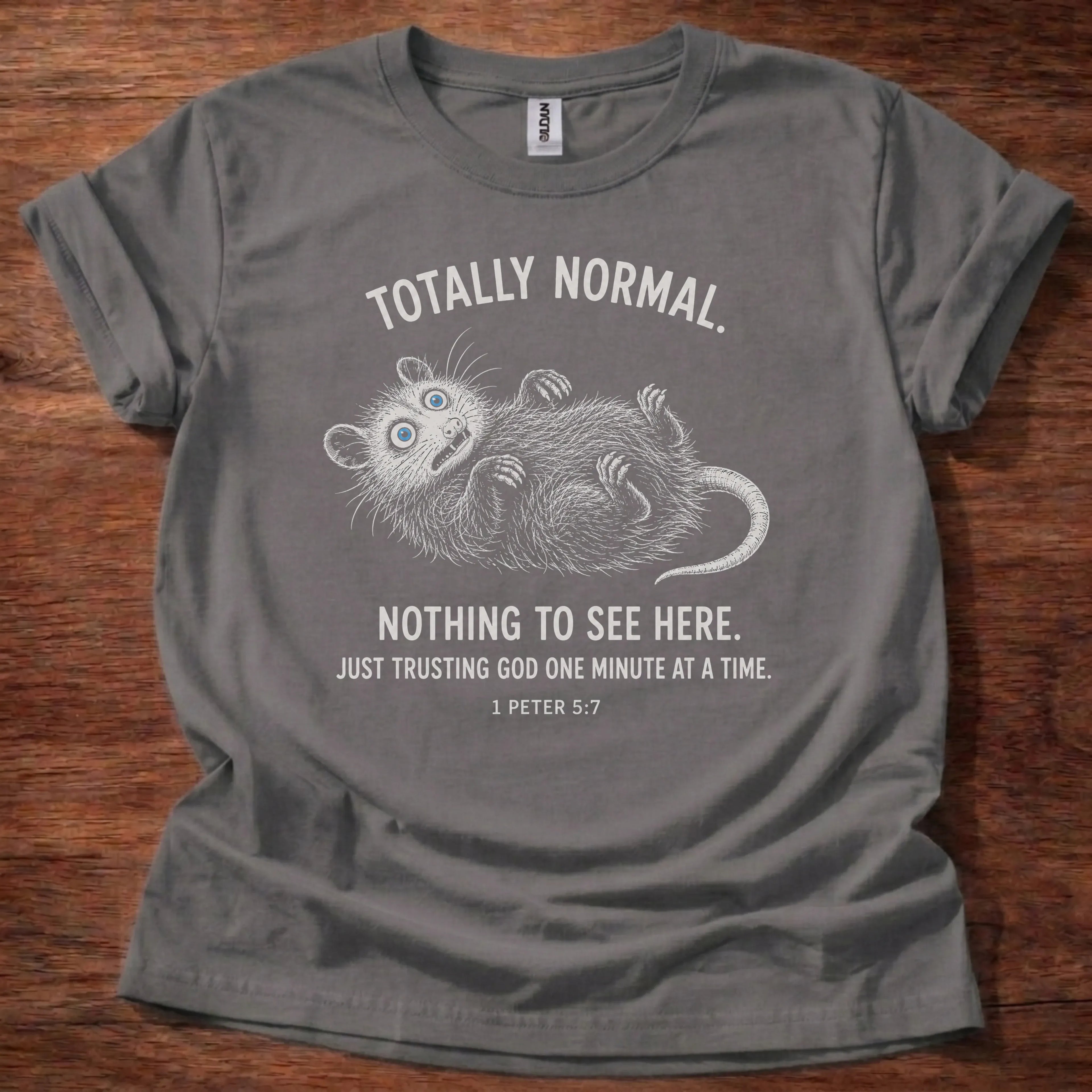 White fine-line opossum illustration playing dead t-shirt with the text 'Totally Normal. Nothing To See Here. Just Trusting God One Minute At A Time.' and 1 Peter 5:7