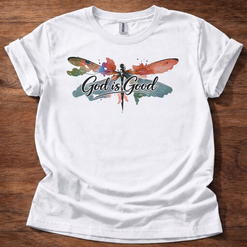 White t-shirt featuring a colorful watercolor dragonfly design with the words “God is Good” printed across the front