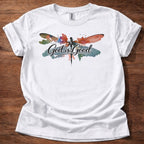 White t-shirt featuring a colorful watercolor dragonfly design with the words “God is Good” printed across the front
