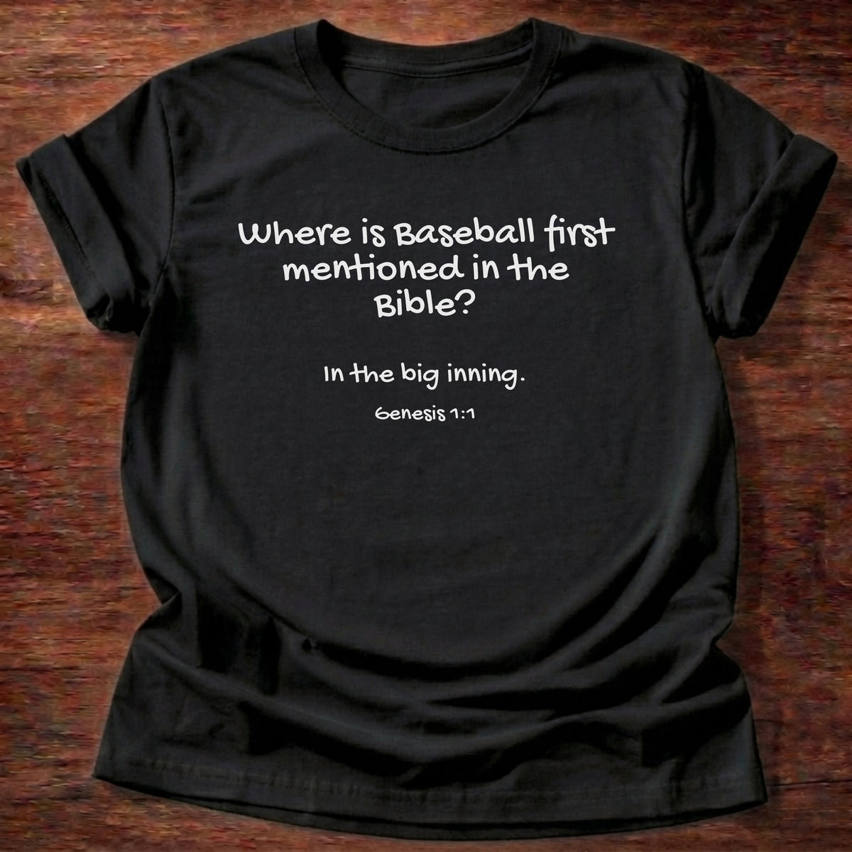 Black t-shirt printed with a simple hand-lettered Bible joke graphic and “Where is baseball first mentioned in the Bible? In the big inning.” Genesis 1:1 Christian shirt