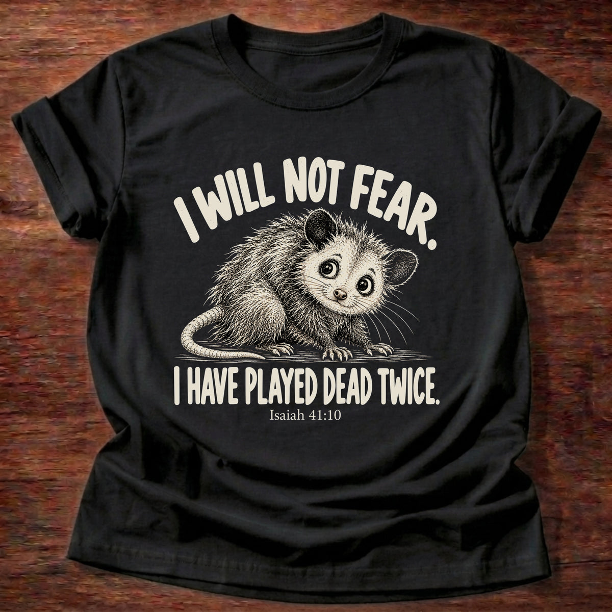 Black t-shirt printed with a wide-eyed opossum graphic and “I will not fear. I have played dead twice.” Isaiah 41:10 Christian shirt