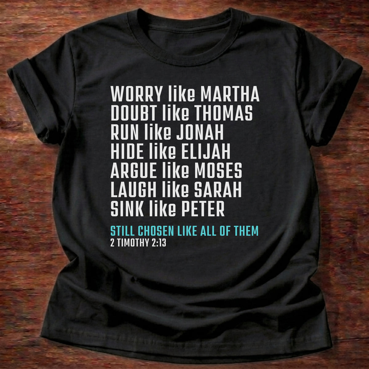 Black t-shirt printed with bold stacked typography listing Bible characters graphic and “Worry like Martha. Doubt like Thomas. Sink like Peter. Still chosen like all of them.” 2 Timothy 2:13 Christian shirt