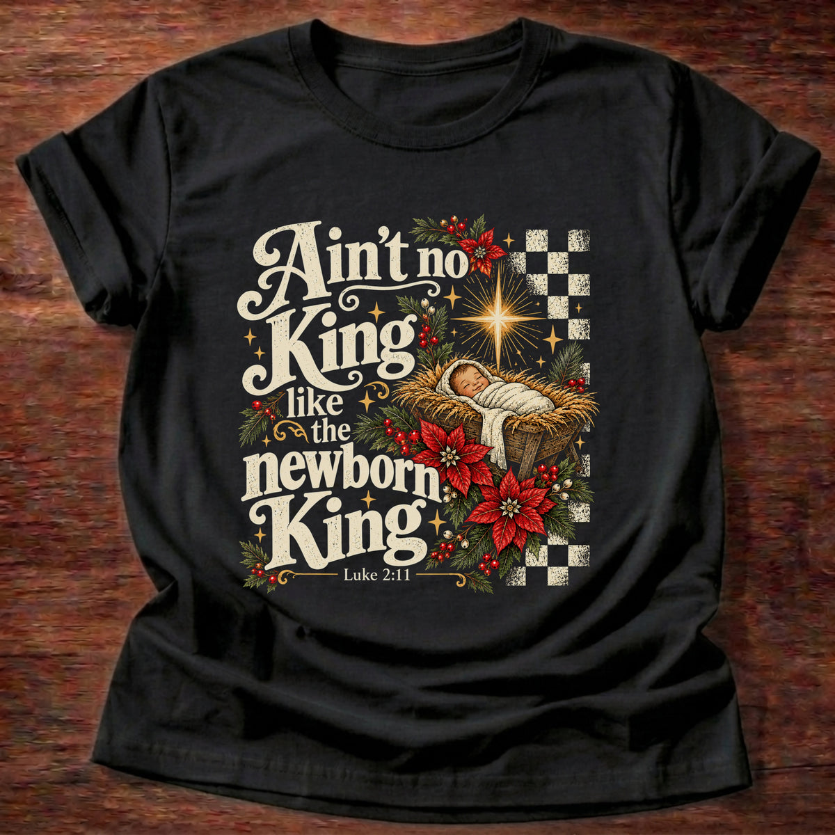 Black t-shirt printed with a retro manger scene with a star, poinsettias and checkerboard graphic and “Ain't no King like the newborn King.” Luke 2:11 Christian shirt