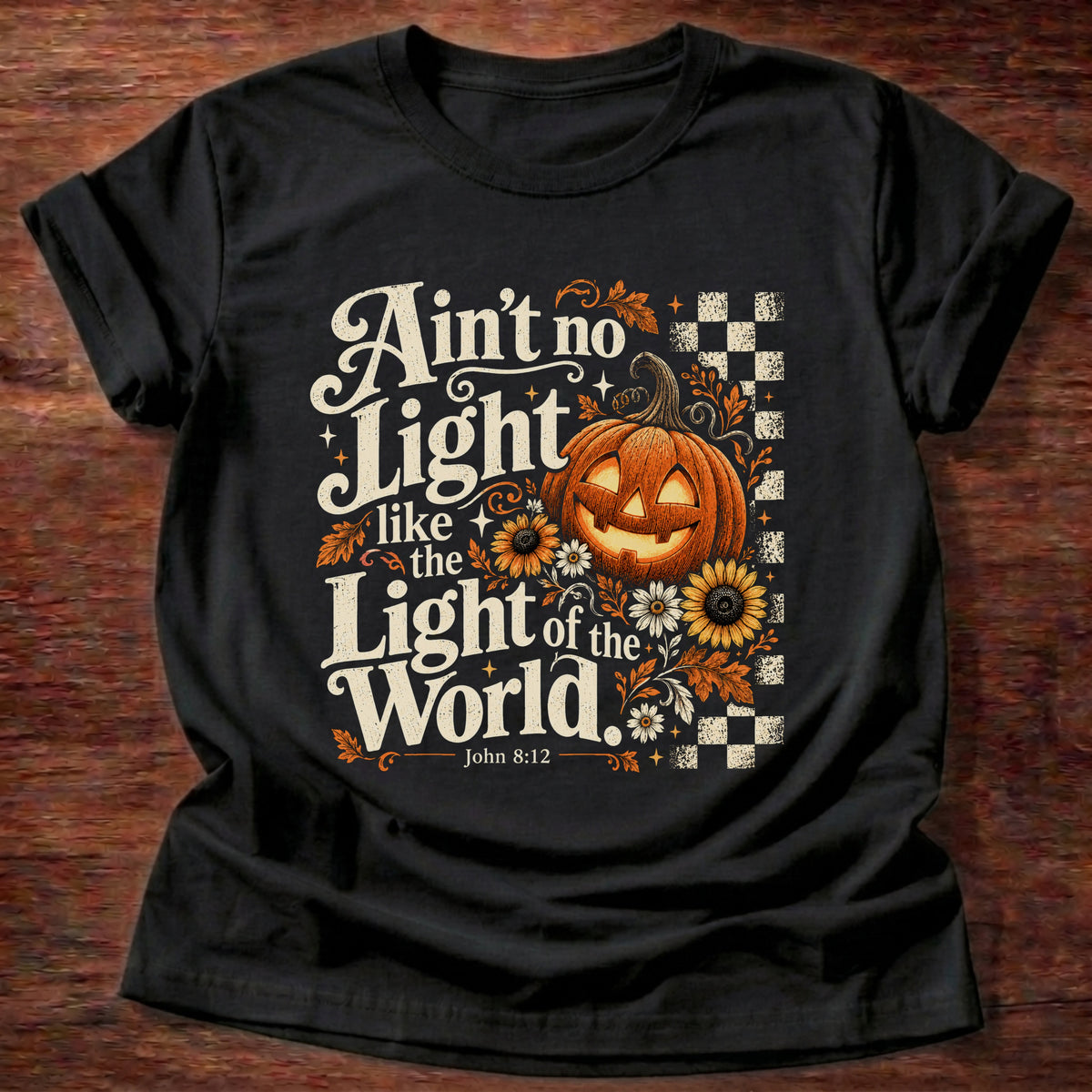 Black t-shirt printed with a retro glowing jack-o'-lantern with sunflowers and checkerboard graphic and “Ain't no light like the Light of the World.” John 8:12 Christian shirt