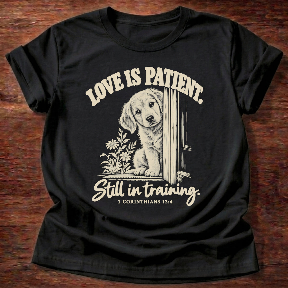 Still In Training T-Shirt in Black featuring a golden retriever puppy peeking around a door and 1 Corinthians 13:4 patience humor design