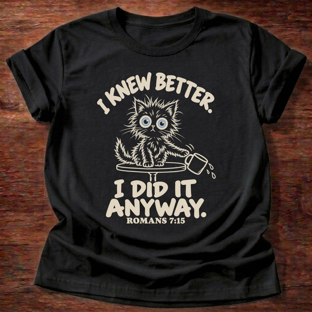 Black t-shirt printed with a scruffy kitten knocking a cup off a table and “I knew better. I did it anyway.” Romans 7:15 Christian shirt