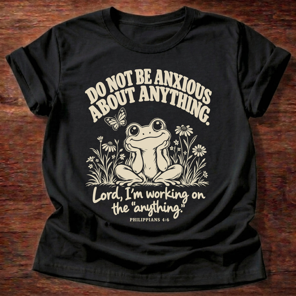 Anything Part T-Shirt in Black featuring a wide-eyed frog sitting among wildflowers and Philippians 4:6 anxiety humor design