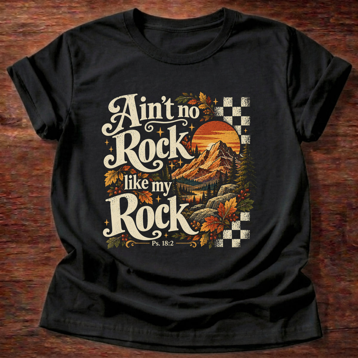 Black t-shirt printed with a retro mountain sunset with autumn leaves and checkerboard graphic and “Ain't no Rock like my Rock.” Psalm 18:2 Christian shirt