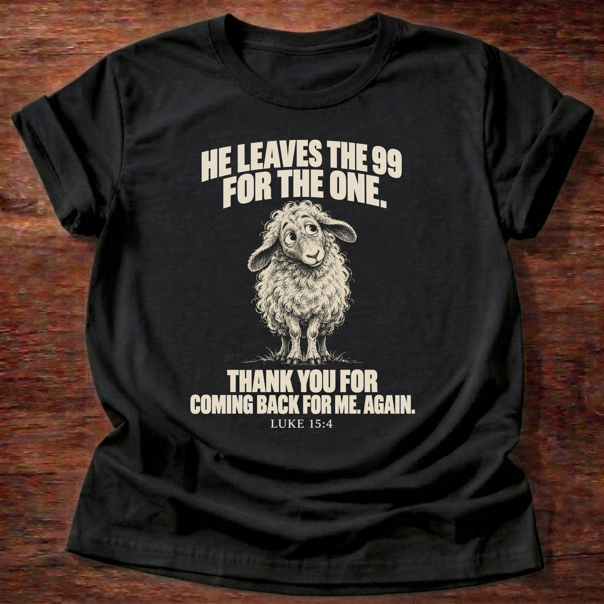Ninety-Nine For One T-Shirt in Black featuring a little lamb looking back with gentle eyes and Luke 15:4 lost sheep grace design