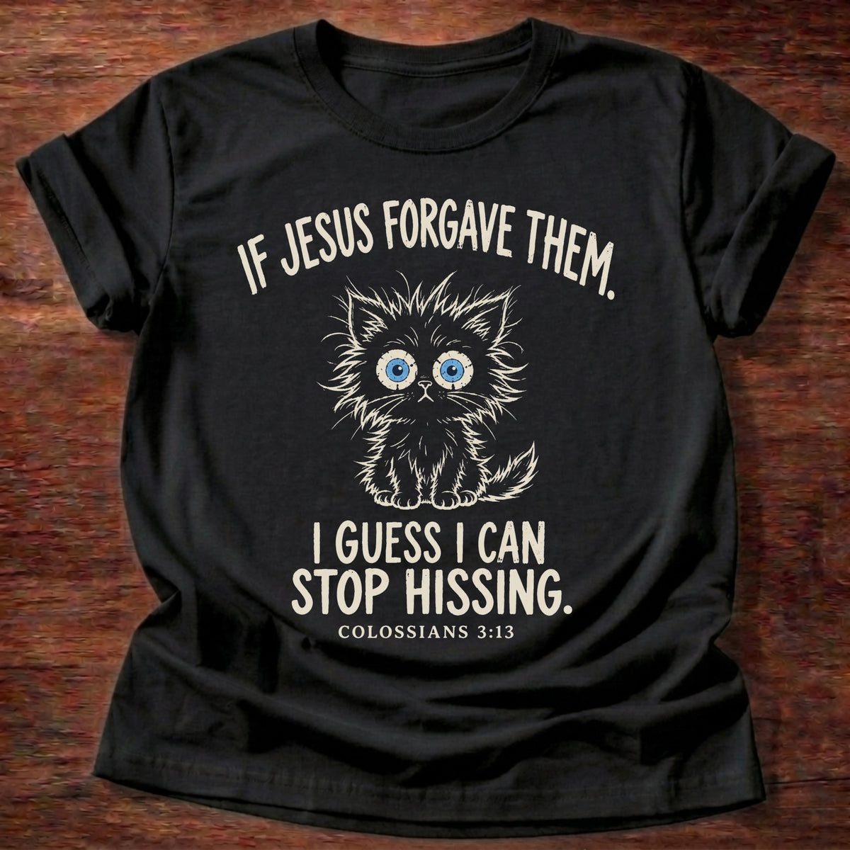 Stop Hissing T-Shirt in Black featuring a fluffy wide-eyed kitten and Colossians 3:13 forgiveness humor design