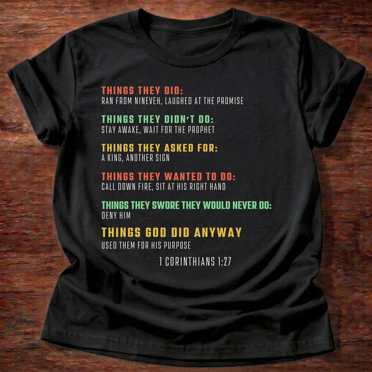 Black t-shirt printed with bold colorful typography listing what Bible heroes did graphic and “Things they did. Things God did anyway.” 1 Corinthians 1:27 Christian shirt