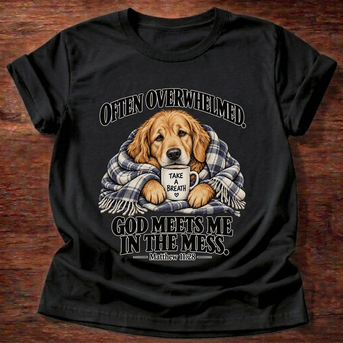 Black t-shirt printed with a golden retriever wrapped in a plaid blanket holding a 'Take a Breath' mug graphic and “Often overwhelmed. God meets me in the mess.” Matthew 11:28 faith based gift