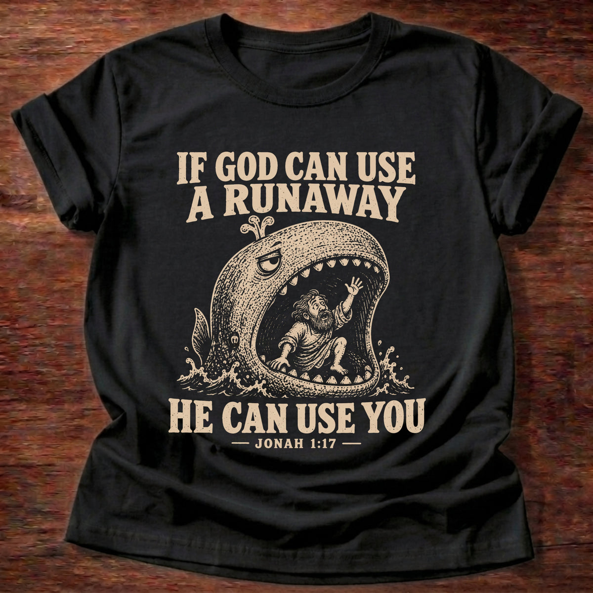 Black t-shirt printed with a whale swallowing a runaway figure and 'If God can use a runaway, He can use you.' Jonah 1:17 faith based gift
