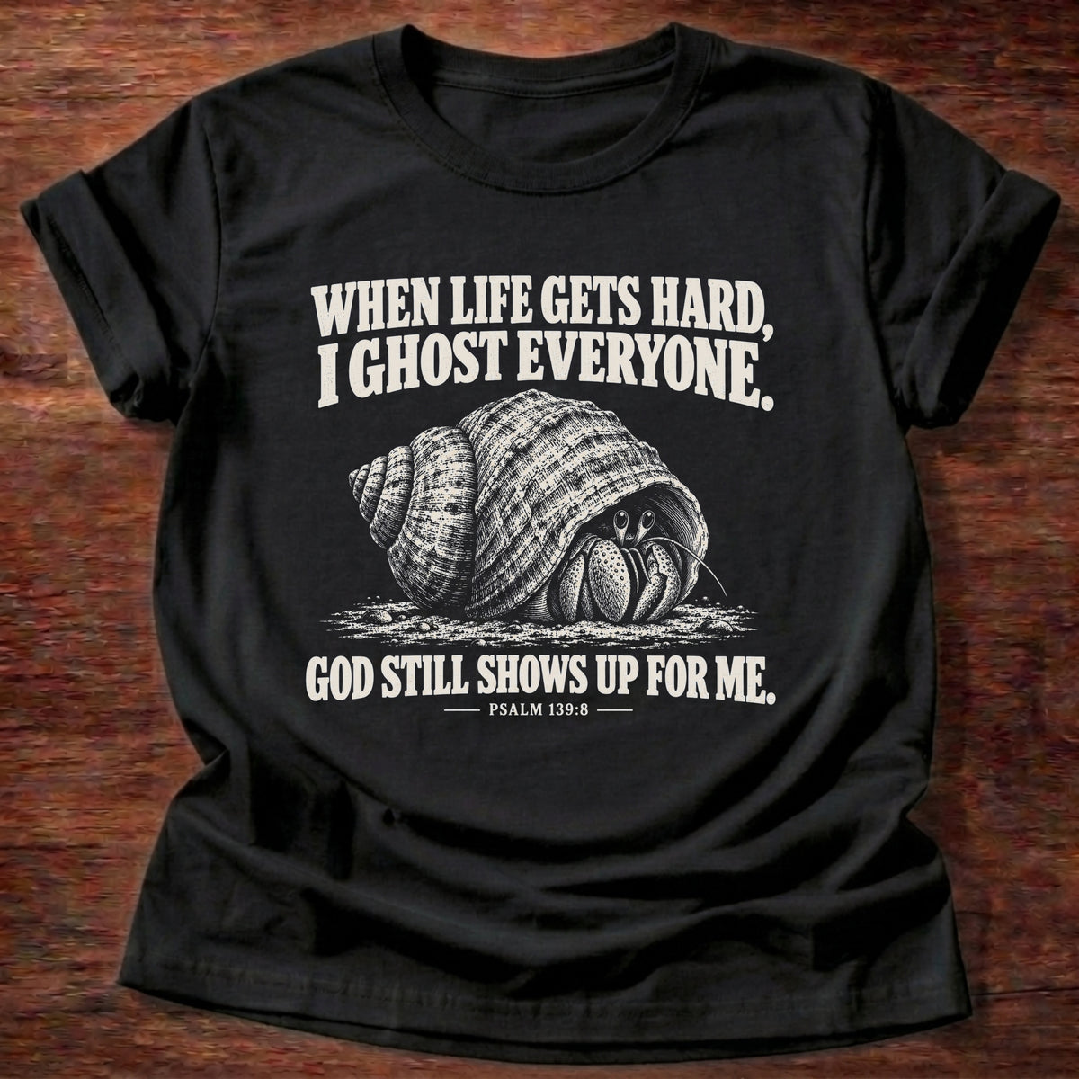 Black t-shirt printed with a hermit crab retreating into its shell graphic and 'When life gets hard, I ghost everyone. God still shows up for me.' Psalm 139:8 faith based gift